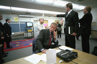 As Deputy Assistant Dan Bartlett points to news footage of the World Trade Center, President George W. Bush gathers information about the attack Tuesday, Sept. 11, 2001, from a classroom at Emma E. Booker Elementary School in Sarasota, Florida. 